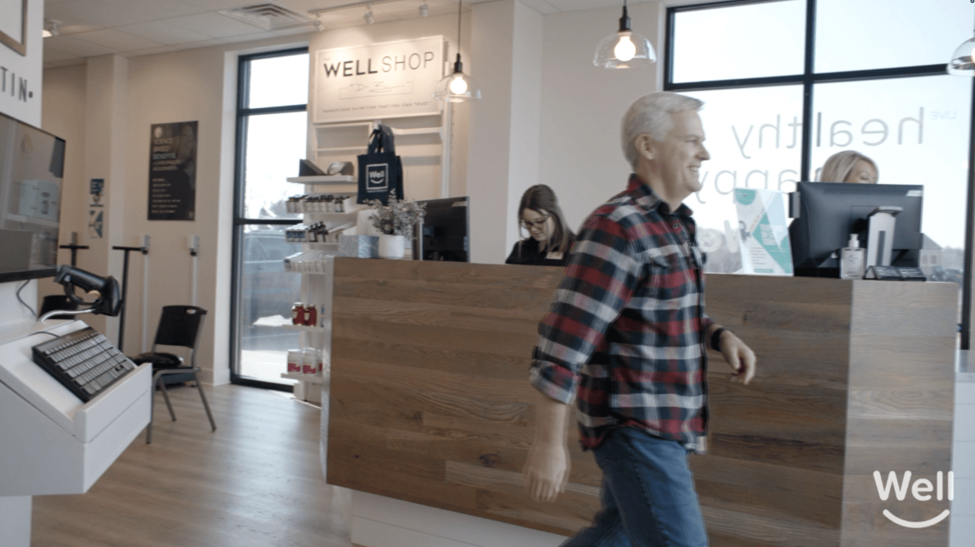 A smiling patient walking through the Well reception area