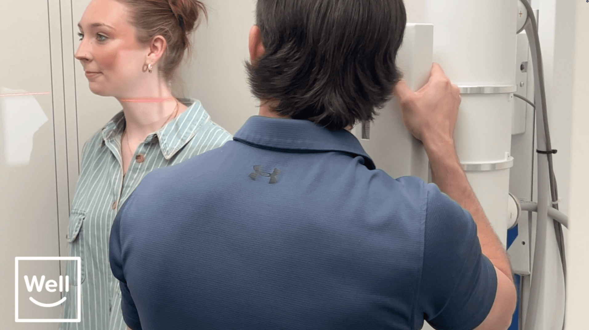 A Well team member aligning digital X-ray equipment beside a patient