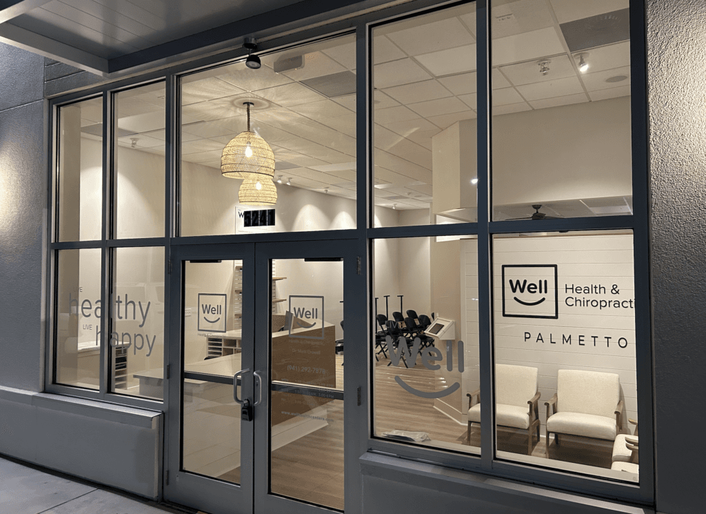 Illuminated storefront entrance at Well Health & Chiropractic Palmetto